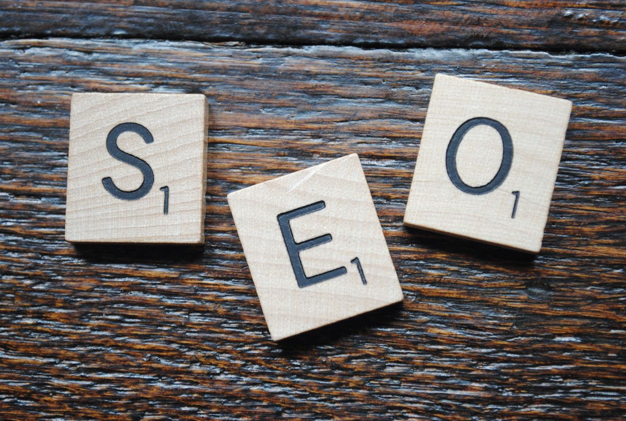 Gros plan de lettres de Scrabble formant SEO sur une table en bois pour une stratégie de contenu.